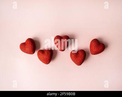 Five red shiny hearts on a pink background. Valentine's day concept. Top view. Copy space. Selective focus Stock Photo