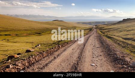 Unpaved road and yurts near Son-Kul lake and Tien shan mountains in Kyrgyzstan Stock Photo