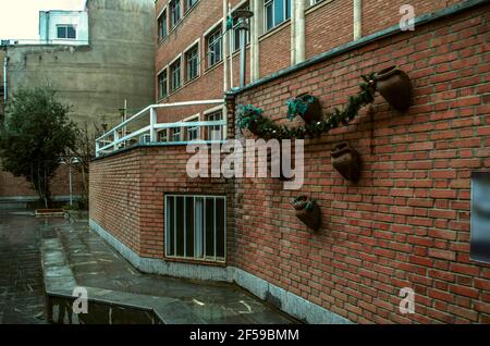 The brick wall of the Museum of arts and crafts, decorated with clay jugs and garlands, is located on the ground floor of the Armenian school in the c Stock Photo