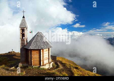 Small wooden church or chapel on the mountain top Col di Lana and cloudy sky, Alps Dolomites mountains, Italy Stock Photo