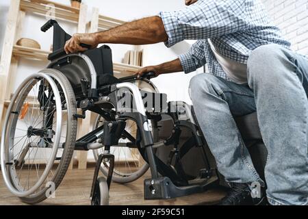 Black disabled man sits down on wheelchair at home Stock Photo