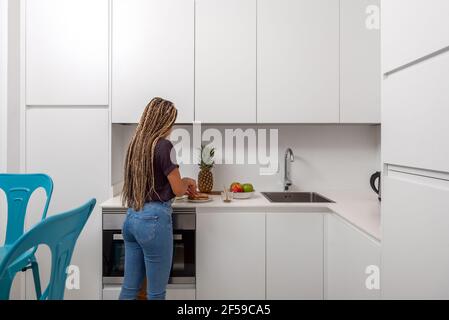 Side view of young female preparing healthy sandwiches for breakfast in light modern home kitchen Stock Photo