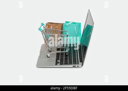 online shopping concept with laptop computer, shopping bag and trolley isolated on white, copy space Stock Photo