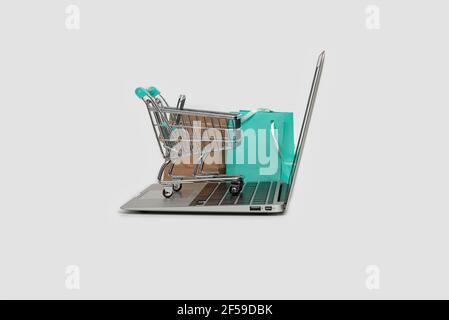 online shopping concept with laptop computer, shopping bag and trolley isolated on white, copy space Stock Photo
