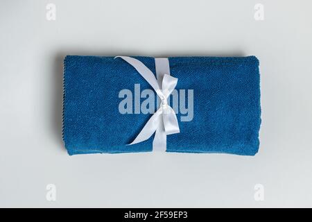 Top view of a rolled up terry blue towel on a light gray background. Stock Photo