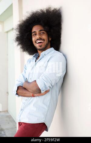 Portrait of happy man leaning on wall with arms crossed outside Stock Photo