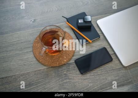 Notebook, action cam, laptop, smart phone and cup of tea on wooden desktop. Recording equipment and shooting video for vlogger and podcasters. Home wo Stock Photo
