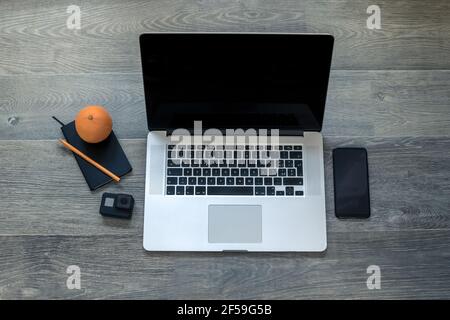 Notebook, action cam, laptop, smart phone and cup of tea on wooden desktop. Recording equipment and shooting video for vlogger and podcasters. Home wo Stock Photo
