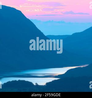 Dreamlike sunset over Buttermere lake in Lake District, UK.Tranquil evening landscape scenery with pink and blue pastel tones.High key nature background. Stock Photo