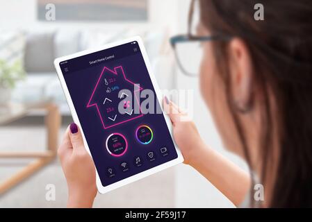 Woman with tablet controls a smart house, temperature, humidity, lighting and security Stock Photo