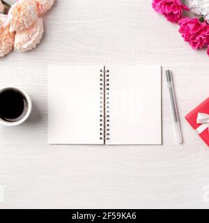 Design concpet of Mother's Day greeting with carnation flower, holiday gift idea and notebook diary on mother's desk background. Stock Photo