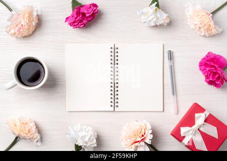 Design concpet of Mother's Day greeting with carnation flower, holiday gift idea and notebook diary on mother's desk background. Stock Photo