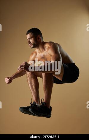 Strong adorable athlete man warming up while working out in gym Stock Photo