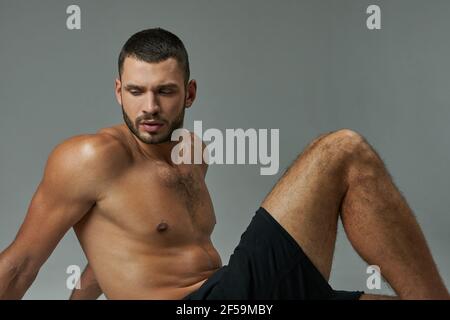 Strong adorable athlete resting after hard practice isolated on grey background Stock Photo