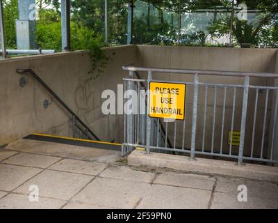 A Please Use Handrail sign on handrails in a stairwell leading to an underground car park at The Mall shopping centre at Cribbs Causeway near Bristol, England. Stock Photo