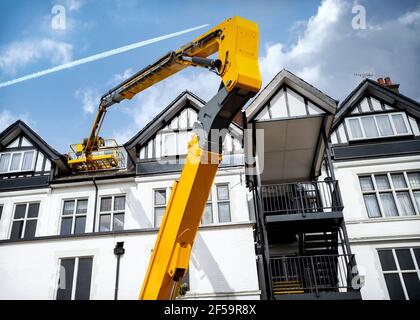 Yellow mechanical elevated working platform hydraulic boom arm extended to work at height MEWP. Cherry picker extended raised high up in air repairs Stock Photo