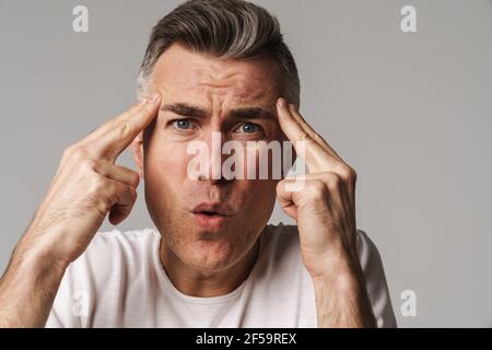 Worried man suffering from headache isolated over gray background Stock Photo