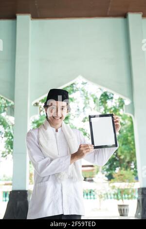 asian man muslim smiling holding blank tablet Stock Photo