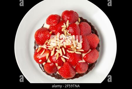 Strawberry pie with almonds, dark chocolate, and vanilla whipped cream. Close up image. Top view on black background. Stock Photo