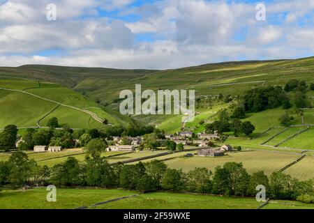 Picturesque Dales village (stone houses) nestling in sunlit valley by fields, hills, hillsides & steep-sided gorge - Starbotton, Yorkshire England UK.