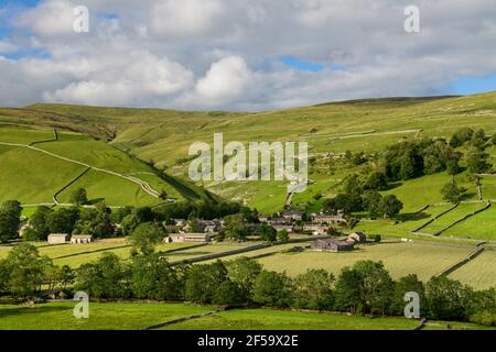 Picturesque Dales village (stone houses) nestling in sunlit valley by fields, hills, hillsides & steep-sided gorge - Starbotton, Yorkshire England UK.