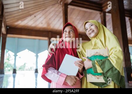 asian kids woman Muslim smiling holding al quran book and hug each other Stock Photo