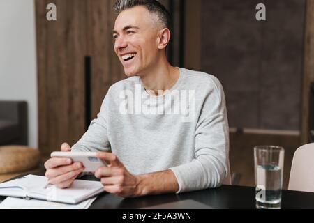 Handsome happy middle aged man using smartphone at home Stock Photo