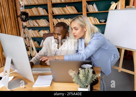 Stylish concentrated coworkers searching ideas for corporate project, using computer. Serious multiethnic colleagues developing new business strategy Stock Photo