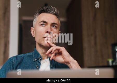 Focused handsome man using laptop while sitting on couch at home Stock Photo