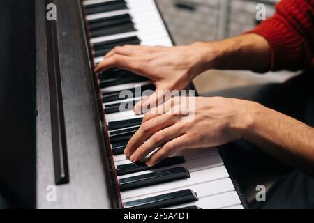 Close-up hands of unrecognizable musician man playing on digital electronic piano synthesize at home. Stock Photo
