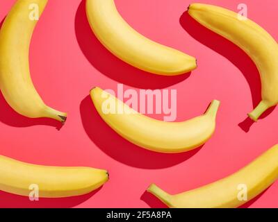 Colorful banana pattern on pink background, from above, hard shadow Stock Photo