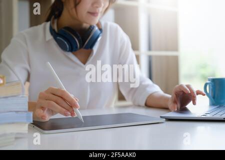 Fashion designer using tablet and sketches while working at table in studio. Stock Photo