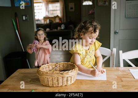 twin toddler girls spending time together in kitchen while coloring