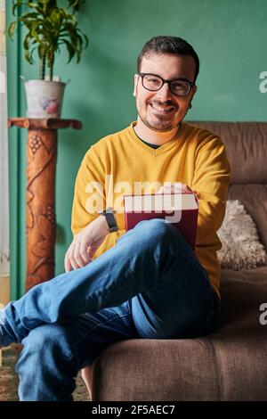 A young man smiles looking at camera in the living room of his home Stock Photo