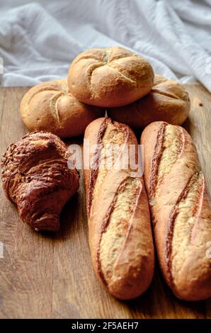 assorted buns and bread on wooden board and white tablecloth Stock Photo