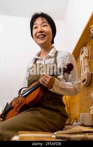 young Chinese violin maker at work in her workshop Stock Photo