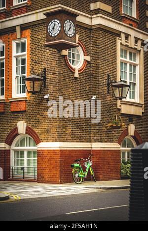 Green bicycle lying on a wall somewhere in London. The bake is safely locked. Contrasty background Stock Photo