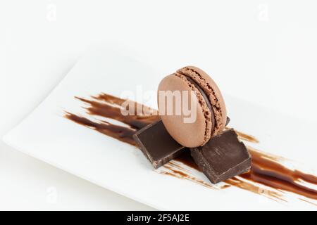 Chocolate macaroons dessert on white background. French meringue cookie macarons with chocolate pieces and chocolate cream. Stock Photo