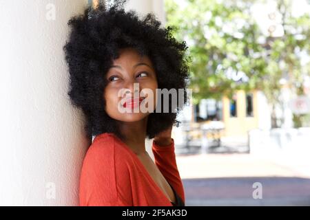 Close up portrait of young woman outside leaning against wall daydreaming Stock Photo