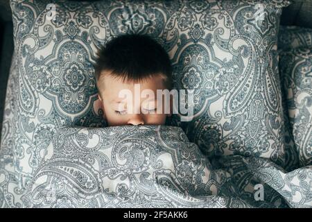 Adorable boy 6-7 years old sleeping in bed. Child having a good dreams Stock Photo