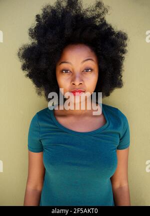 Portrait of serious young woman standing by wall staring Stock Photo