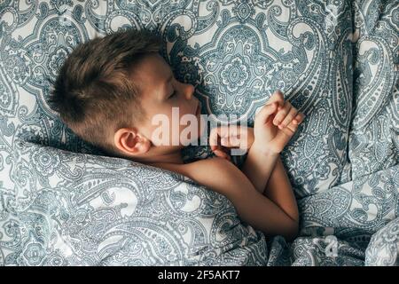 Adorable boy 6-7 years old sleeping in bed. Child having a good dreams. Top view Stock Photo