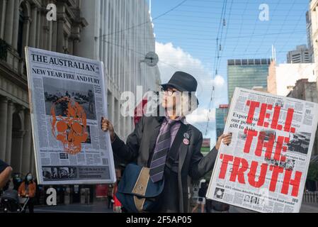 Melbourne, Australia. 25th March 2021. Along with flags and banners, Extinction Rebellion protesters created large mock newspapers with reports of extreme weather events and climate issues in Australia. This follows a week of disruptive action by the group in order to raise public and federal awareness of climate change. Credit: Jay Kogler/Alamy Live News Stock Photo