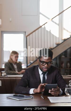 African young businessman using digital tablet while working online sitting in coffee shop Stock Photo