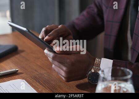 Close-up of African man typing on digital tablet while working at his workplace at office Stock Photo