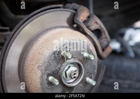 Old thin ventilated brake disk with used brake pads are ready for replacing, close-up view Stock Photo