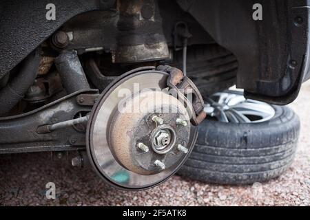 Old steel ventilated brake disk with rusty support brake pads are ready for removing, rear wheel Stock Photo