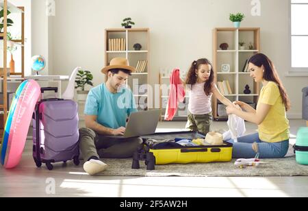 Family going to travel father buying ticket online mother packing clothes Stock Photo