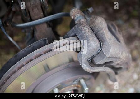 Rusty ventilated brake disk with used brake pads in calliper, close up view Stock Photo