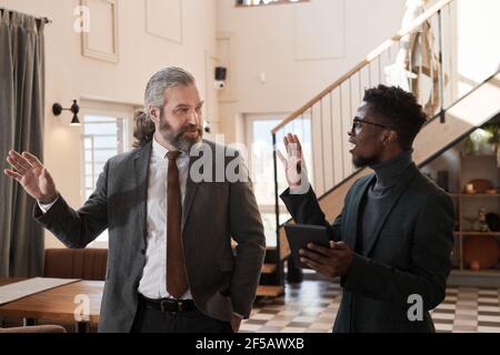 Two business colleagues using digital tablet and discussing the organization of business meeting in the restaurant Stock Photo